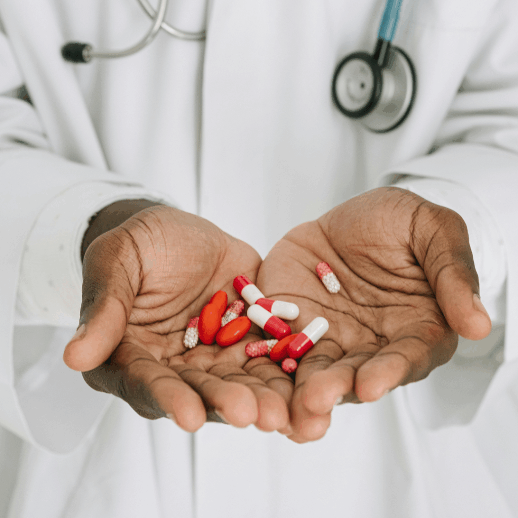 Pharmacist holding red and white capsules in hand.