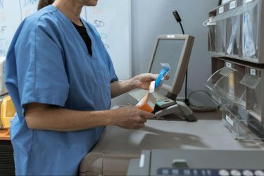 A pharmacist in blue scrubs is fulfilling an order.